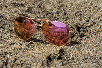 Fototapeta na wymiar Sunglasses at the beach with beach ball reflection. Holidays, travel, vacation and happiness concept.
