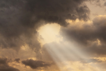 Sunlight penetrates through thick dark clouds during the sunset_