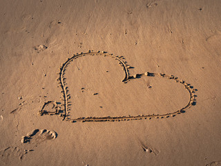 Girl writes a heart symbol in the sand on a beach - travel photography
