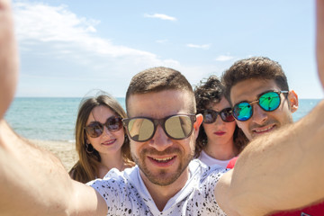 Obraz premium Friends in sunglasses celebrate Summer and make a group selfie at the beach in vacation