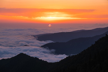 Sunset in the mountains. Large cumulus clouds over the mountains. Forest in the mountains. Evening light. Time to rest and enjoy. No people.