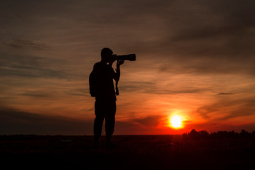 Photographer silhouette with camera at sunset