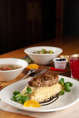 Close up of a roasted pork cutlet with boiled bulgur and greens as a part of set meal in a restaurant