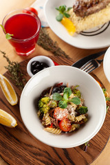 Vegetarian pasta with greens, broccoli and olives, sprinkled with fragrant parmesan, served on a dark wood board