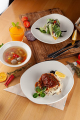 Set lunch menu in a restaurant: fish with steamed rice, light vegetable soup with meatballs and vegetarian spring roll