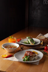 Meal deal for lunch: fish with steamed rice, light vegetable soup with meatballs and vegetarian spring roll on a dark background