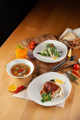 Lunching out in a restaurant: fish with steamed rice, light vegetable soup with meatballs and vegetarian spring roll on a dark background