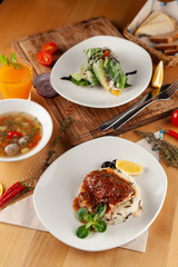 Lunching out in a restaurant: fish with steamed rice, light vegetable soup with meatballs and vegetarian spring roll on a dark background