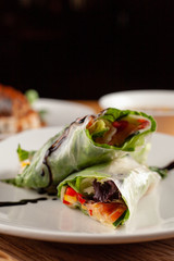 Yummy vegetarian spring rolls in a rice paper with carrot, greens, bell pepper and cucumber
