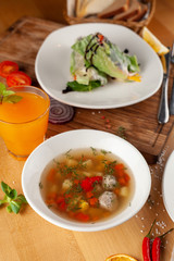 Summer light soup with vegetables and meatballs for the first course and vegan spring rolls for the second course as a part of healthy mid day meal