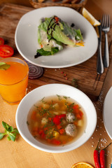 Summer light soup with vegetables and meatballs for the first course and vegan spring rolls for the second course as a part of healthy mid day meal