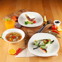 Steak with mashed potatoes, light vegetable soup with meatballs and vegetarian spring roll for healthy diet lunch, placed on a wooden table with sidelight