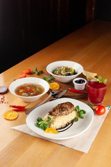 Steak with boiled bulgur, hot soup with meatballs and vegan pasta with veggies and olives as a nutritious lunch in a cafe