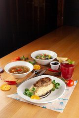 Steak with boiled bulgur, hot soup with meatballs and vegan pasta with veggies and olives as a nutritious lunch in a cafe