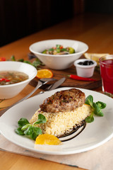 Steak with boiled bulgur, hot soup with meatballs and vegan pasta with veggies and olives as a nutritious lunch in a cafe