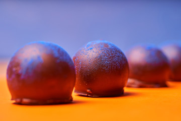 Chocolates with blue algae on colored background.
