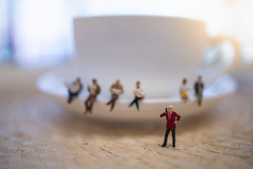 Close up of group of businessman miniature figure standing and make phone call with white cup of coffee.