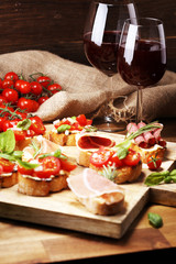 antipasto various appetizer. Cutting board with prosciutto, salami, cheese, bread and olives on dark wooden background
