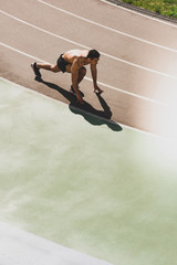 overhead view of mixed race sportsman preparing to run at stadium