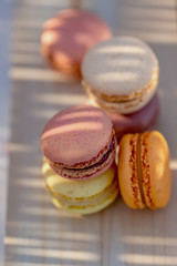 Delicious sweet French pastries on a rustic table. Dessert macarons in the summer evening in the orchard. Sunlight.