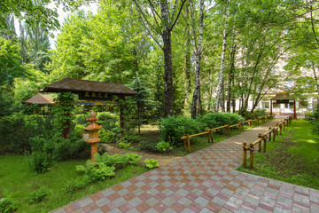 summer chinese garden with yellow pathway, tea pagoda on green summer background