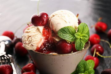 Cherry and vanilla ice cream scoop with fresh cherries and mint on a rustic background