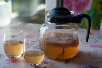 A Kombucha spilled into glasses that lives in a glass teapot