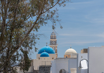 Fototapeta na wymiar Skyline with clock tower and domes in village of Fira on Santorini