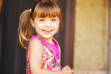 petite fille blonde en robe rose avec un grand sourire