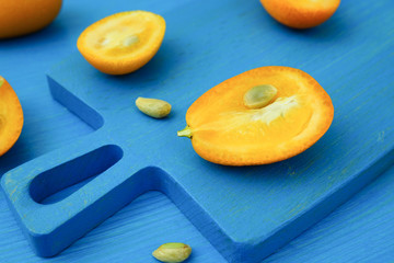 Kumquat fruits. Cut kumquat on a blue cutting board. Close-up.