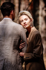 stylish blonde young woman with husband in forest