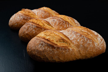 Freshly baked tasty bread on a dark table. Tasty baked goods straight from the bakery.