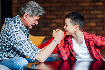 Strong grandfather playing with his grandson on home.