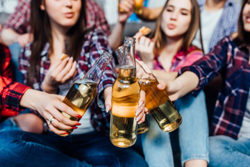 Group of friends cheering with beers at home interiour,close up..