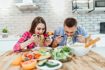 Portrait of cute happy in cheeful action tasting and smelling breakfast of macaroni table decorated with ingredient of food in modern kitchen..