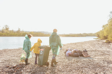 Photo of the back. Young  family  volunteers after picking up trash on the beach. Help nature together.