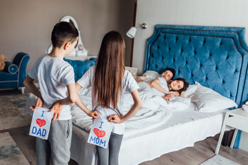 A young family  lying on bed , they young children  in the bedroom  with picture.
