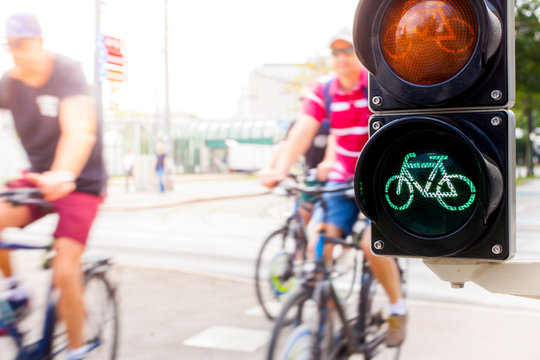 Grüne Fahrradampel mit Radfahrer in Bewegung. Cyclists passing green bicycle traffic light.