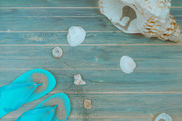 Flip-flops with marine items on wooden background.