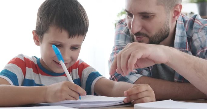 Man guiding his son doing homework in notebook