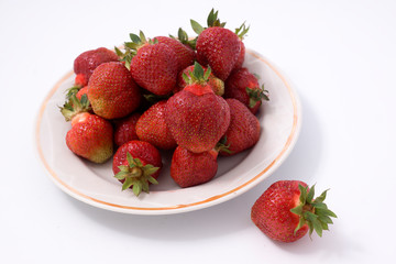 Heap of fresh strawberries in ceramic bowl on rustic white wooden background.
