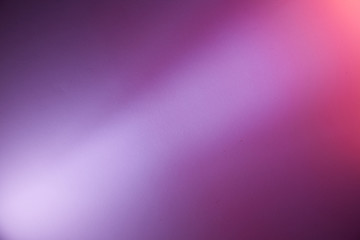 Bright diagonal diffuse ray of light on a purple and pink background
