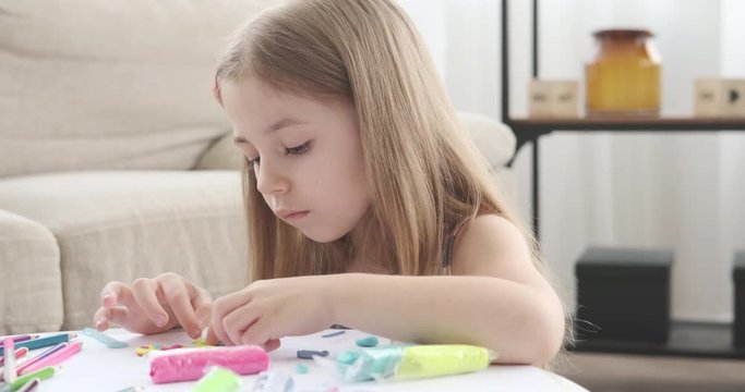 Cute girl playing with plasticine on drawing paper