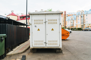 Grey electric Transformer room building with white doors and yellow hazard signs in the city on...