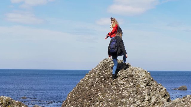 Two young women climb on the rocks of Giants Causeway in Northern Ireland - travel photography