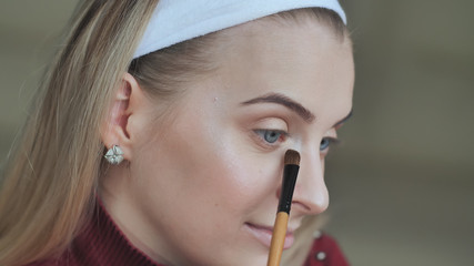 Blonde girl does her own eye makeup.