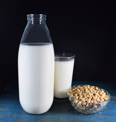 Botella y vaso de leche de soja, bol con granos de soja  