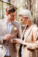 Smiling and happy man making marriage proposal to beautiful woman in forest