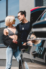 Fototapeta na wymiar selective focus of stylish man and beautiful girl posing near car