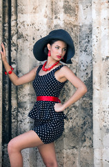 Young attractive woman wearing black dress and red high heels shoes posing at the Plaza de la Catedral in Havana, Cuba